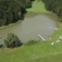 Luftaufnahme vom Badeteich am Pilgramhof in Friesach: Steg, Liegewiese und Wald rundum – ideal für Urlaub am Bauernhof Kärnten, Bauernhof mit Badeteich Kärnten und Bauernhofurlaub mit Kindern Kärnten.