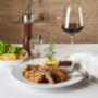 Paniertes Kürbiskern-Schnitzel mit Preiselbeersauce, Erdäpfelsalat und Blattsalat, serviert mit Rotwein im Silberwirt in Wien – traditionelle österreichische Hausmannskost.