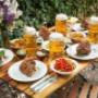 Große Tafel im Gastgarten des Silberwirt mit knuspriger Stelze, Beilagen, Salaten und Krügen Bier – gemütlicher Wiener Gastgarten für typisch österreichisches Essen.