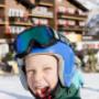 Kind mit Skihelm auf Skipiste vor Familienhotel Sonnenburg