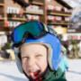 Kind mit Skihelm auf Skipiste vor Familienhotel Sonnenburg Kind mit Skihelm auf Skipiste vor Familienhotel Sonnenburg