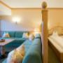 Komfortdoppelzimmer im Sonnenburg Landhaus mit Doppelbett und grüner Sofalandschaft