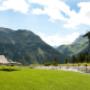 Liegestuhl auf Wiese mit Bach und Bergpanorama Lech