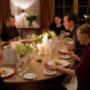 Festliches Abendessen an ovalem Tisch mit mehreren Gästen