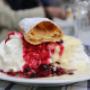 Süßer Nachtisch im Klostergasthof beim Stift Heiligenkreuz: luftige Schlagobershaube mit Beerenragout, Vanillesauce und Brandteiggebäck – perfekter Stopp am Kloster bei Wien, Ausflugsziele Niederösterreich.
