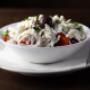 Frischer Shopska-Salat im Restaurant Galaxie Wien mit Tomaten, Gurken, Paprika, Zwiebeln, Oliven und geriebenem Schafskäse. Beliebte Vorspeise aus der Balkan-Küche.