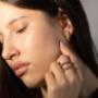 Model mit goldenen Creolen und Diamantbesatz sowie mehreren feinen Ringen in Gold und Silber – luxuriöser Schmuck mit stilvoller Kombination, Ausdruck von Eleganz und zeitloser Schönheit.
