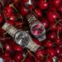 Zwei Rolex Day-Date Modelle gebettet in Kirschen: links mit elegantem grauen Zifferblatt, rechts mit einem leuchtend roten Zifferblatt. Ein Kontrastspiel zwischen klassischer Zurückhaltung und auffälliger Extravaganz.
