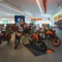 Große Innenansicht bei KTM Händler Wien: mehrere KTM Bikes im Verkaufsraum, dazu Bekleidung & Motorradzubehör.