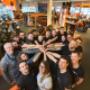 KTM Wien Team im KTM Flagshipstore: Mitarbeiter im Kreis im Showroom mit KTM Motorrad Modellen & Motorradzubehör – KTM Wien GmbH mit Werkstatt.