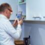 Ein Mann liest mit einer Licht-Lupenbrille von VIDEBIS die Details in der Küche