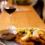 Klassisches Wiener Schnitzel mit Petersilkartoffeln, Preiselbeeren und Zitrone im Bummelhof. Österreichische Hausmannskost im gemütlichen Restaurant auf der Mariahilfer Straße – beliebtes Essen in Wien 1070.