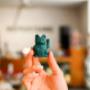Eine kleine dunkelgrüne Winkekatze (Maneki Neko) – ein modernes Deko-Accessoire, das Glück und Wohlstand symbolisiert. Minimalistisch im Design, perfekt als Geschenk oder stilvolle Dekoration für Zuhause und Büro.