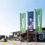 Außenansicht des Standorts von Aggstein Edelbrände mit kostenlosem Kundenparkplatz, Firmengebäude und Fahnen im Eingangsbereich. Gepflegtes Betriebsgelände mit einladender Atmosphäre, klarer Markenpräsenz und regionalem Unternehmenscharakter.