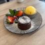 Süßer Genuss im Wiener Genussladen (1060 Wien): Warmer Schokokuchen mit Vanilleeis und Beeren. Das perfekte Dessert nach einem Besuch im Haus des Meeres oder für eine gemütliche Wiener Jause.