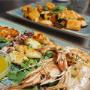 Frische italienische Meeresfrüchte-Spezialitäten im Casa Borbone Wien. Gegrillte Garnelen und Calamari, serviert auf Rucola mit hausgemachter Zitronensauce, kombiniert mit Paccheri-Pasta in fruchtiger Tomatensauce und Meeresfrüchten. Authentische süditali