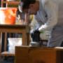 Detailarbeit beim Schleifen eines massiven Holzschrankes. Professionelle Restaurierung und Lackvorbereitung vom Malermeister in Mödling.