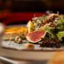 Frischer Feigen-Salat mit warmem Ziegenkäse, Nüssen & Kernen, Microgreens und Zitronenspalte – leicht & aromatisch. Café Bellaria Wien: moderne österreichische Küche, ideal fürs gesunde Mittagessen.