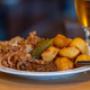 Zwiebelrostbraten mit knusprigen Bratkartoffeln, Essiggurke und Röstzwiebeln – deftiger Klassiker aus der Wiener Wirtshausküche im Bieriger Wien.