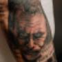 Realistisches Tattoo im Black-and-Grey-Stil: ein intensives Porträt des Jokers kombiniert mit Schriftzügen. Gestochen bei Happy Needles Tattoo Wien – präzise Schattierungen und starke Kontraste machen dieses Tattoo zu einem Highlight für Realismus-Fans.
