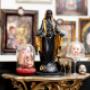 Das Foto zeigt detailreiche Dekorationen im Studio Happy Needles. Zentral steht eine schwarze Statue mit goldenen Akzenten, daneben befinden sich in Glasglocken arrangierte Puppenköpfe, die kunstvoll tätowiert und gestaltet sind. Ergänzt wird die Szene du