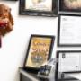 Dieses Bild zeigt einen kunstvollen Altar im Tattoo-Studio Happy Needles. Im Zentrum steht ein Triptychon mit Heiligenmotiven im Tattoo-Stil, versehen mit Ornamenten, Rosen und Totenkopfdetails. Im Hintergrund sind weitere kunstvolle Wandteppiche und Bild