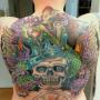 Farbenfrohes Rücken-Tattoo mit Totenkopf, Krone, Meerjungfrau und leuchtenden Ornamenten. Ein Meisterwerk von Happy Needles Tattoo in Wien – perfekt für Liebhaber von großflächigen Tattoos mit kräftigen Farben und Symbolik.