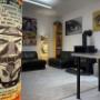 Innenansicht des Ateliers von Christian Beran in Wiener Neudorf: Pop-Art & Siebdruck, Lounge-Bereich mit Ledersofas, Kaminofen und Galerie-Wänden – Ort für Auftragsarbeiten, Ausstellungen und Workshops.