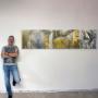 Atelier in Wiener Neudorf: Künstler neben großformatigem Mixed-Media/Siebdruck in Grau-Gelb. Zeitgenössische Kunst, Corporate Art, Auftragsarbeiten & Workshops – Studio für individuelle Kunstprojekte.