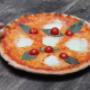 Knusprige Pizza Margherita mit Tomatensauce, Mozzarella, Cherrytomaten und Basilikum in der Trattoria Margareta – italienisches Restaurant in Wien mit authentischer Pizza aus dem Steinofen.