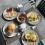 Kreative Frühstücksgerichte mit Pancakes, Eggs Benedict, belegtem Brot, Porridge und Kaffeespezialitäten im sonnigen Gastgarten des Café-Restaurant Resselpark Wien – moderner Genussmoment nahe Karlsplatz.