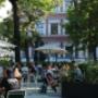Belebter Gastgarten eines Café-Restaurants im Resselpark nahe Karlsplatz Wien – schattige Sitzplätze im Grünen, entspannte Kaffeehaus-Atmosphäre und beliebter Treffpunkt für Mittagspause und Restaurantbesuche.