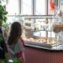 Gäste vor der Tortenvitrine mit einer Auswahl an Kuchen und Desserts im Café Ponykarussell im Wiener Prater.