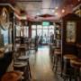 Gemütliches Pub-Ambiente im Trinity Pub Vienna in Wien: Der urige Innenbereich mit Holztheke und Barhockern lädt zu Craft Beer und Cocktails ein.